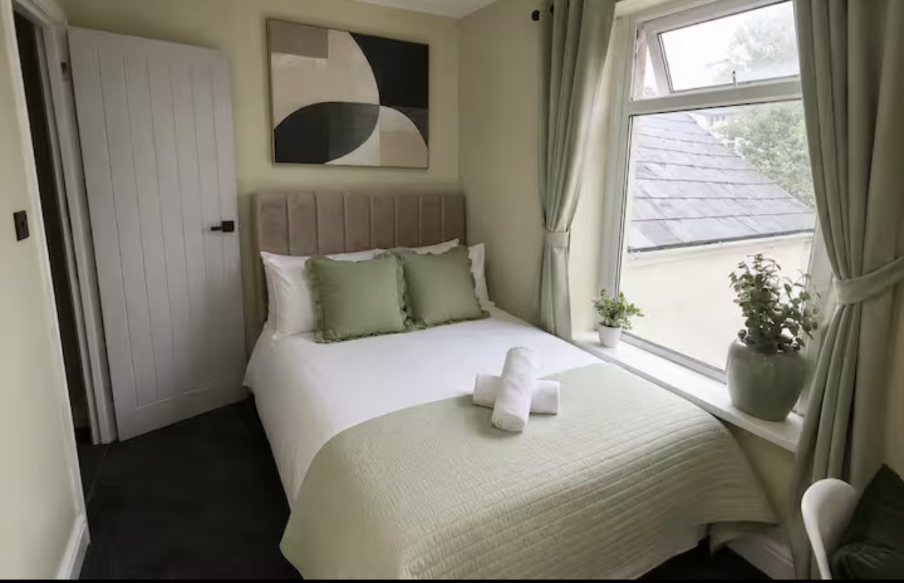 Double bedroom with sage green cushions and curtains