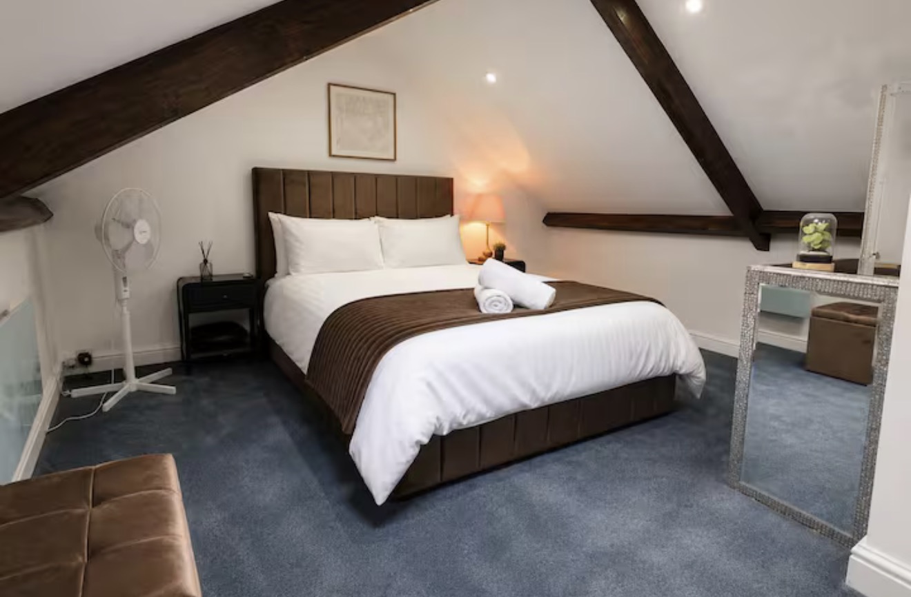 Loft bedroom with exposed wooden beams and a double bed